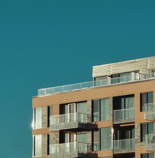 Stylish urban apartment building exterior with glass balconies under a clear sky.